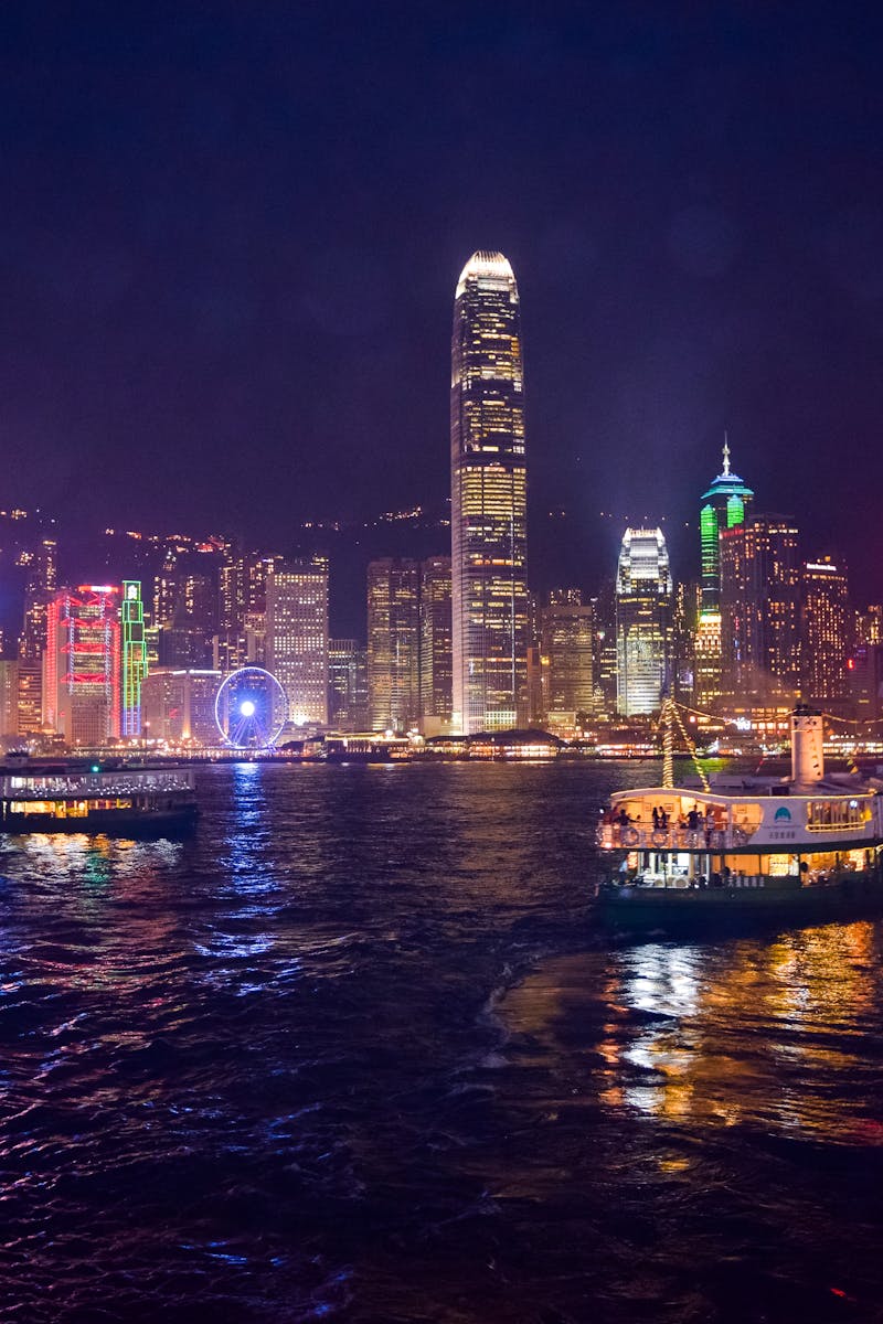Captivating night view of Hong Kong's illuminated skyline and ferries reflecting on the water.