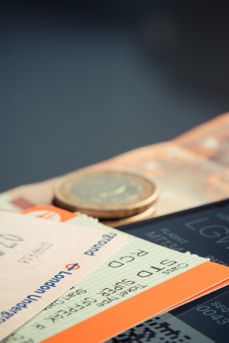 Airline ticket with euro coins and smartphone displaying flight details.